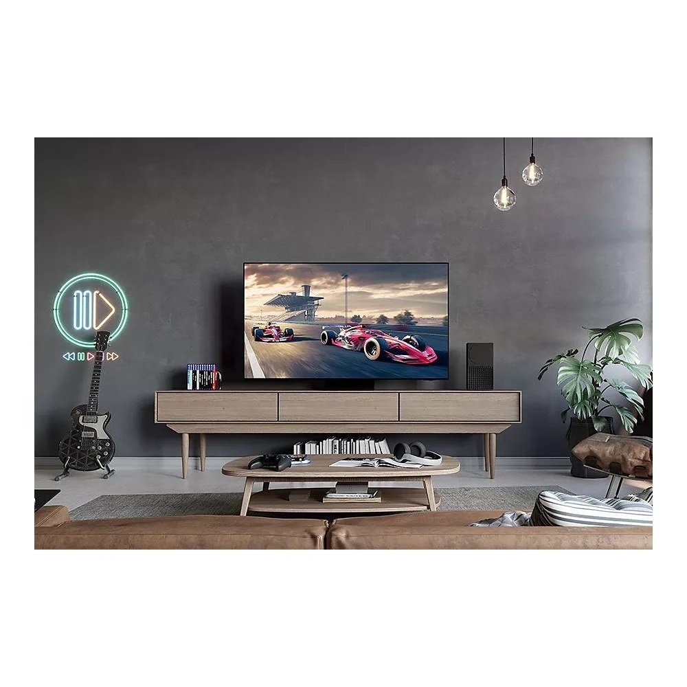 Le salon présente une décoration moderne, un élégant téléviseur SAMSUNG TQ77S95D avec un jeu de course, une guitare élégante dans le coin et des néons vibrants sur le mur.