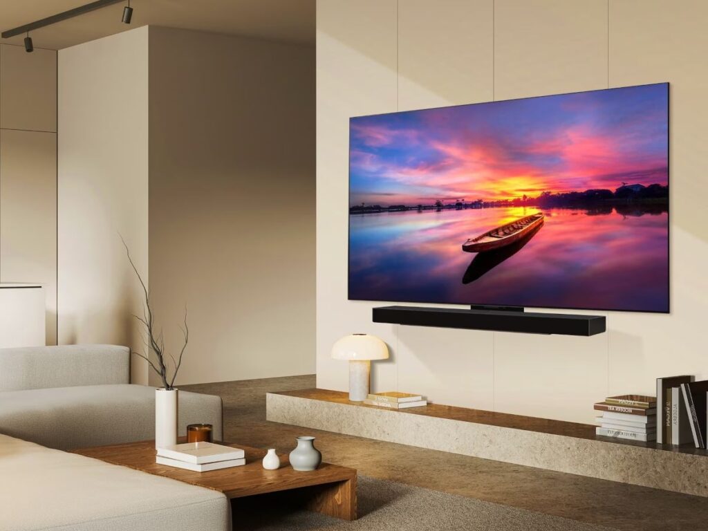 Salon minimaliste doté d'un téléviseur mural LG OLED77C4 présentant un bateau au coucher du soleil, ainsi que de meubles modernes et d'une lampe blanche posée sur une étagère.