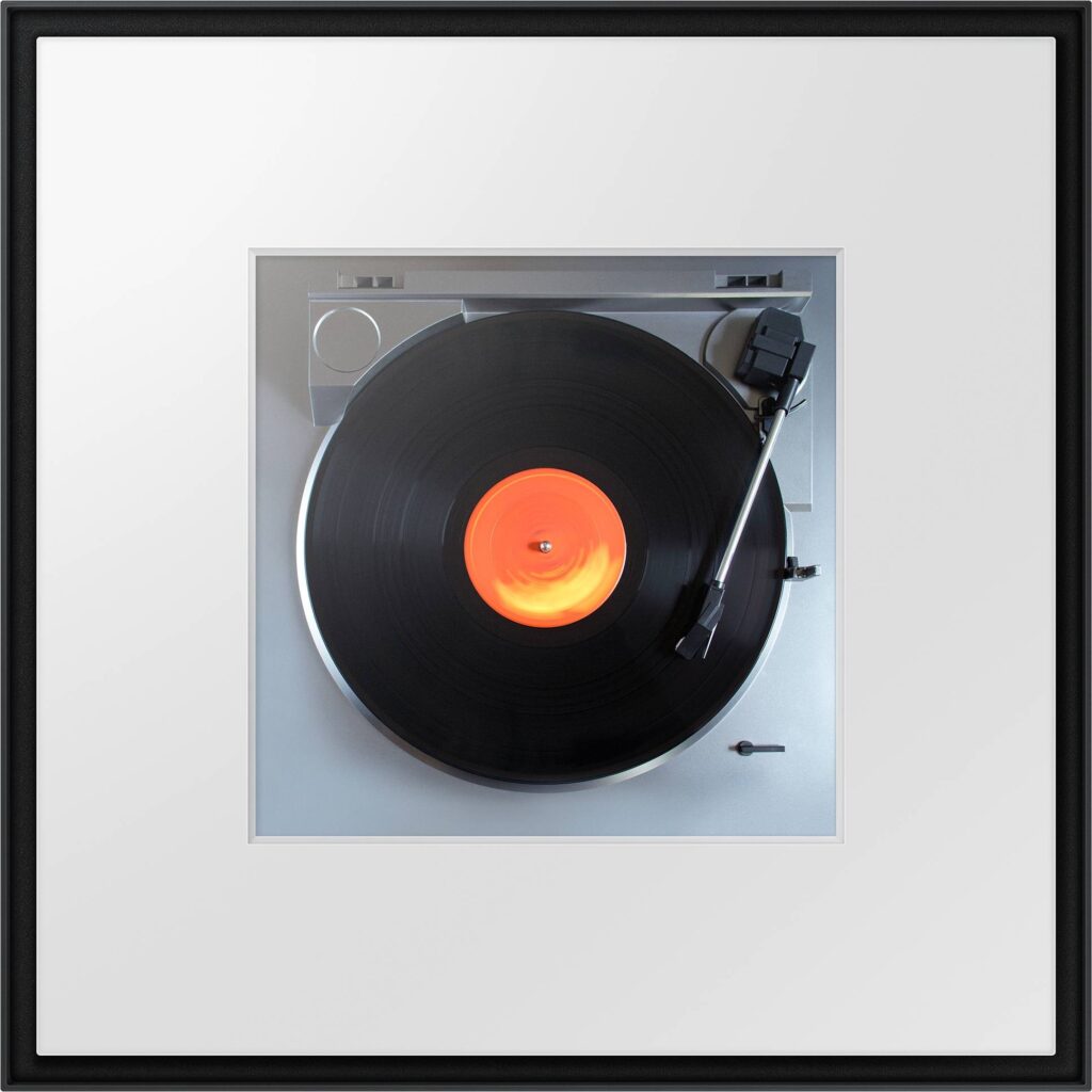 Une image encadrée d'un disque vinyle tournant sur une platine, avec le système audio sophistiqué SAMSUNG HW-LS60D améliorant l'ambiance.