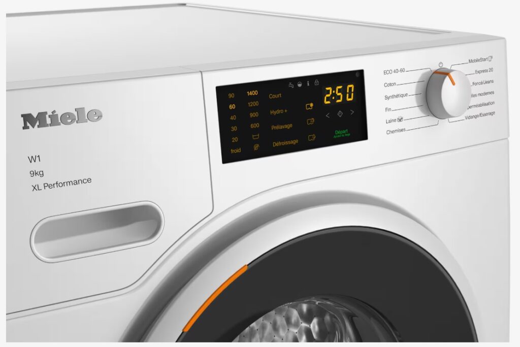 Gros plan d'une machine à laver MIELE WWD164 WCS blanche avec un cadran circulaire orange et un affichage numérique indiquant 2:50, dotée de la technologie WCS innovante.