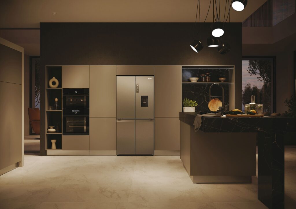 Une cuisine moderne avec un îlot central, un réfrigérateur en acier inoxydable, un four intégré HAIER HCW58F18EWMP et des luminaires contemporains.