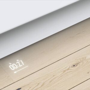 Un affichage d'horloge numérique projeté sur un plancher en bois clair à côté d'armoires de cuisine blanches et d'un élégant lave-vaisselle intégré BOSCH SMV6ECX00E.