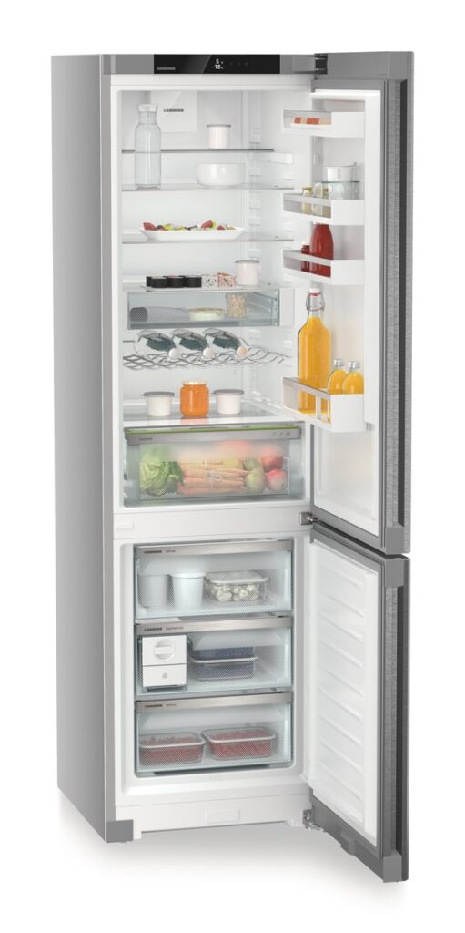 Un réfrigérateur en acier inoxydable LIEBHERR CNSDA5723-22 avec ses portes grandes ouvertes, affichant des étagères méticuleusement organisées remplies d'un assortiment d'aliments et de boissons.