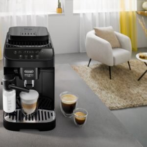 Une machine à café moderne noire DELONGHI ECAM293.52B MAGNIFICA est posée sur le comptoir de la cuisine avec deux tasses de café riche et un salon confortable en arrière-plan.