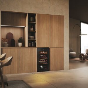 Cuisine moderne avec armoires en bois, réfrigérateur à vin HAIER HWS34GGH1 et étagères ouvertes. Coin repas minimaliste avec chaises et table.