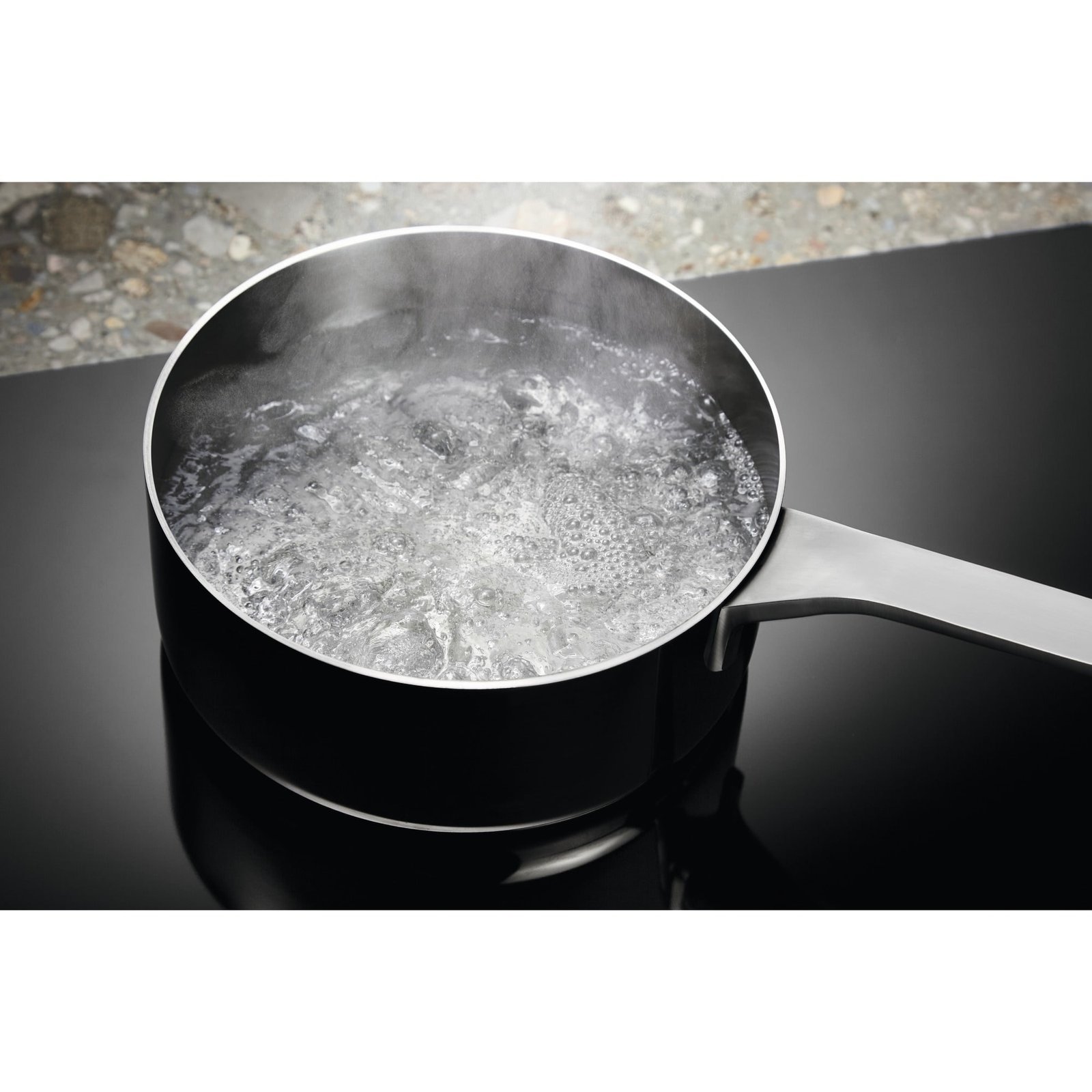 Une casserole d'eau bouillante sur la surface noire et élégante de la table de cuisson à induction ELECTROLUX EIV63343.