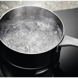 Une casserole d'eau bouillante sur la cuisinière noire et élégante de l'ELECTROLUX IDE6342KC.