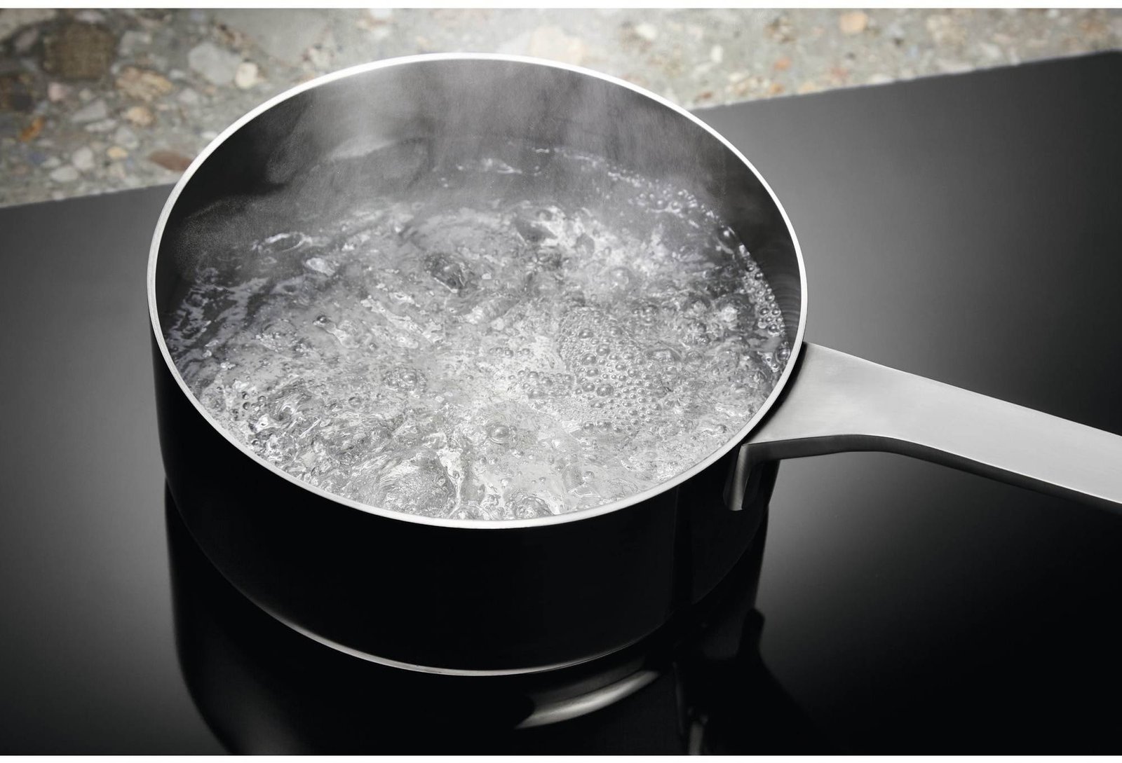 Une casserole d'eau bouillante sur la cuisinière noire et élégante de l'ELECTROLUX IDE6342KC.
