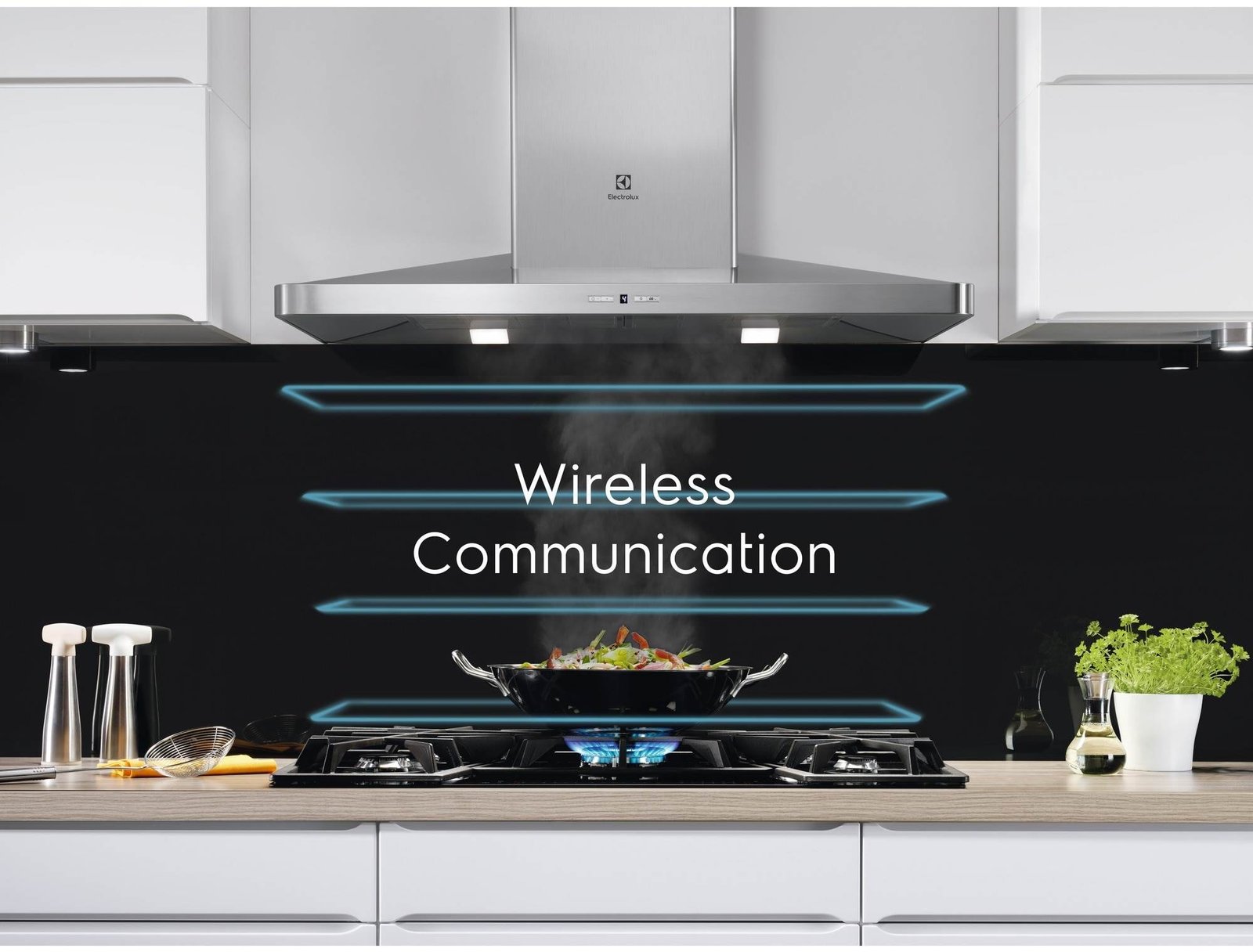 Dans une cuisine moderne, une table de cuisson grésille de légumes dans un wok, tandis que les mots « Communication sans fil » s'illuminent sur un dosseret noir rétroéclairé, mettant en vedette l'élégant ELECTROLUX IDE6342KC pour une expérience de cuisson innovante.
