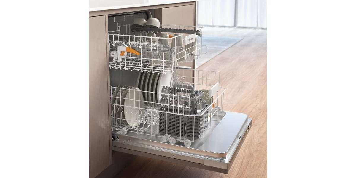 Ouvrez le lave-vaisselle MIELE G 5150 VI, rempli d'assiettes, de bols et d'ustensiles, situé dans une cuisine moderne dotée de parquet.
