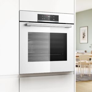 Le four BOSCH HBA572BW3F, avec son design encastré blanc élégant et ses commandes numériques, complète avec élégance le mobilier en bois clair de la salle à manger.