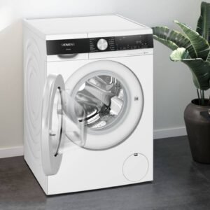 La buanderie moderne est élégamment décorée d'une élégante machine à laver à chargement frontal SIEMENS WG44G2F2FR blanche, complétée par une plante en pot et des vêtements soigneusement pliés à proximité.
