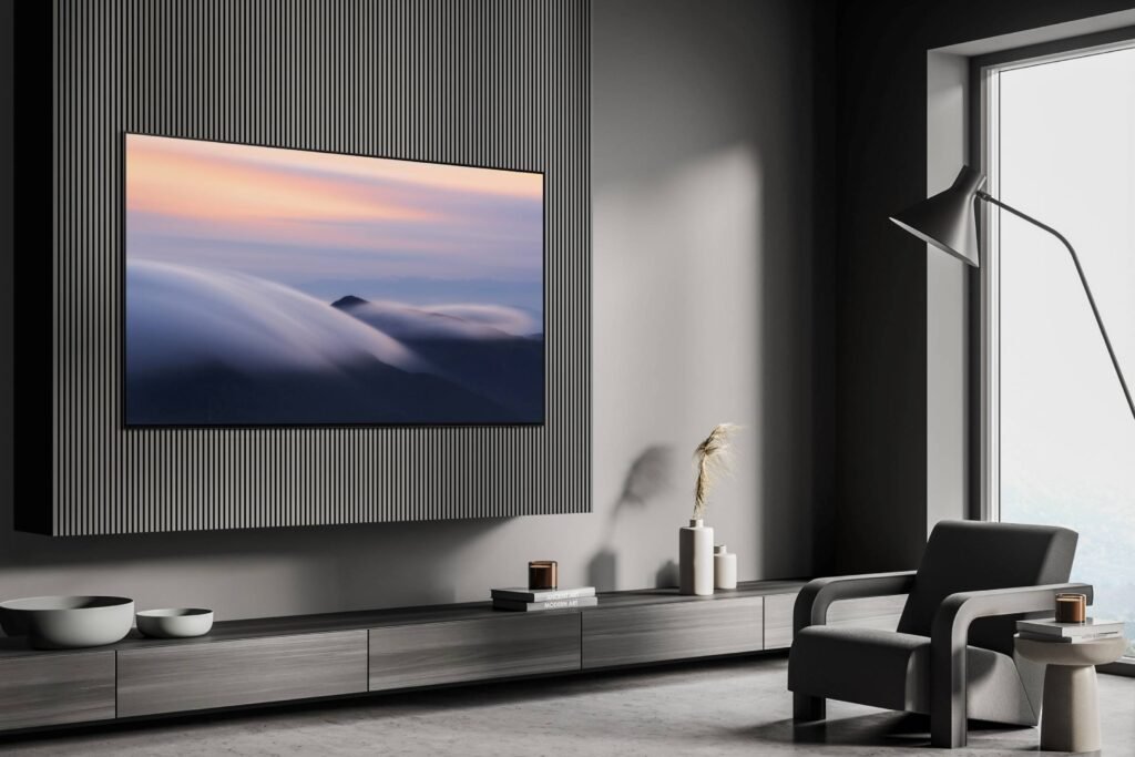 Un salon contemporain met en valeur l'élégant téléviseur intelligent SAMSUNG TQ77S90D monté au-dessus d'un fauteuil. Un lampadaire chic ajoute de la chaleur et une grande fenêtre offre une vue sereine.