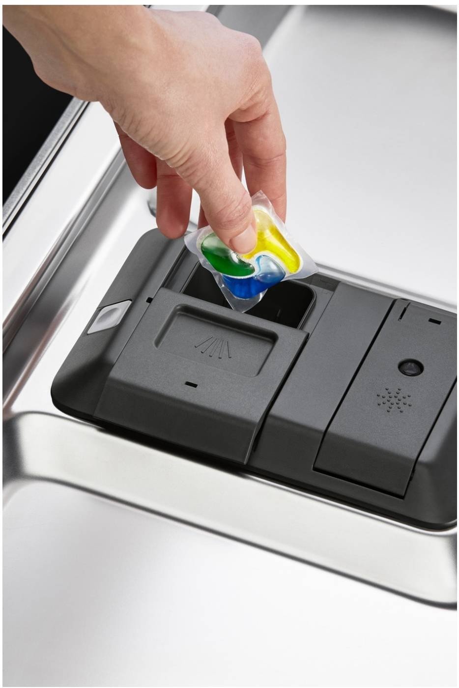 Une main insère une dosette de détergent vibrante dans le compartiment de l'élégant lave-vaisselle ELECTROLUX EES48320L.