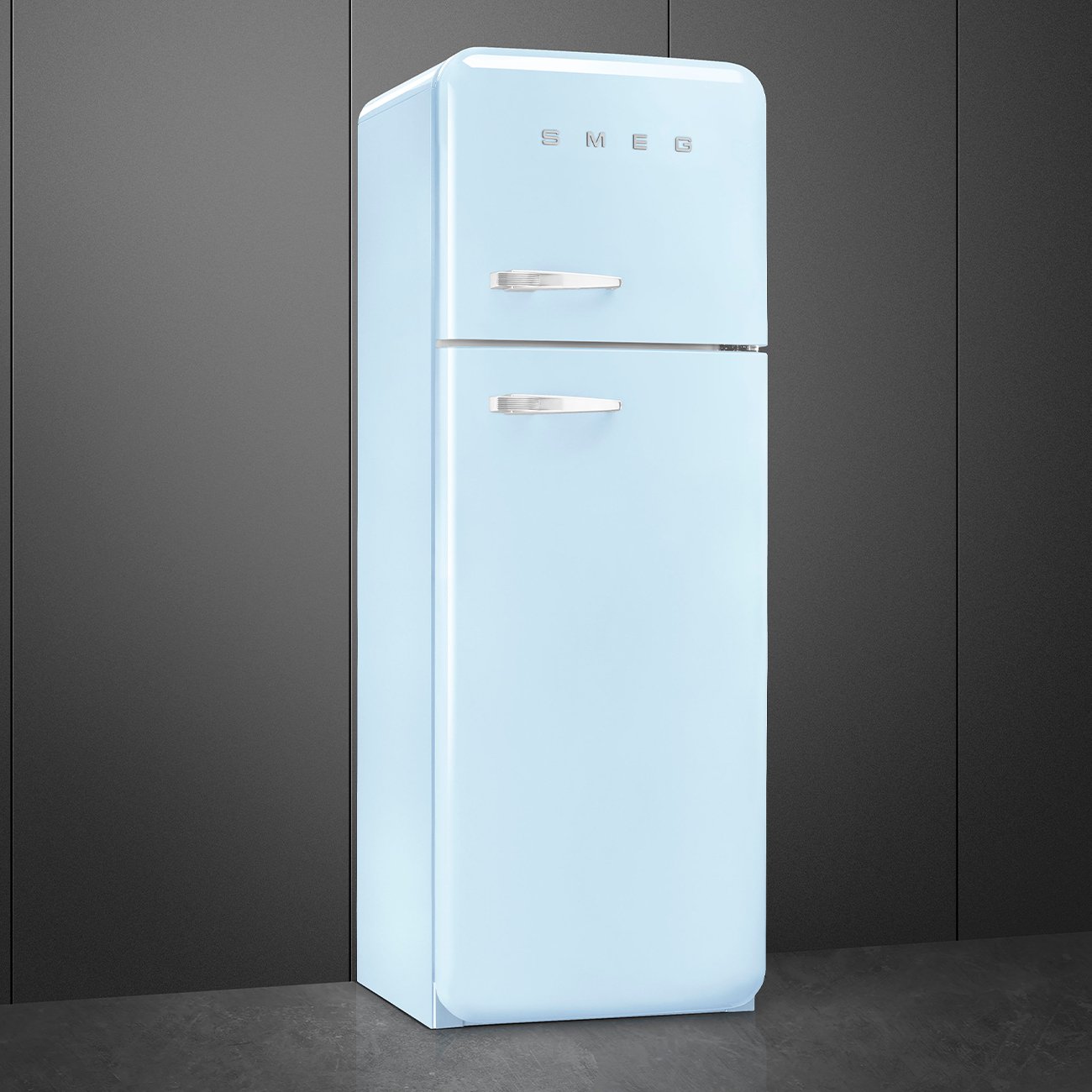 Un réfrigérateur SMEG FAB30RPB5 bleu clair avec poignées chromées est placé contre un mur gris foncé.