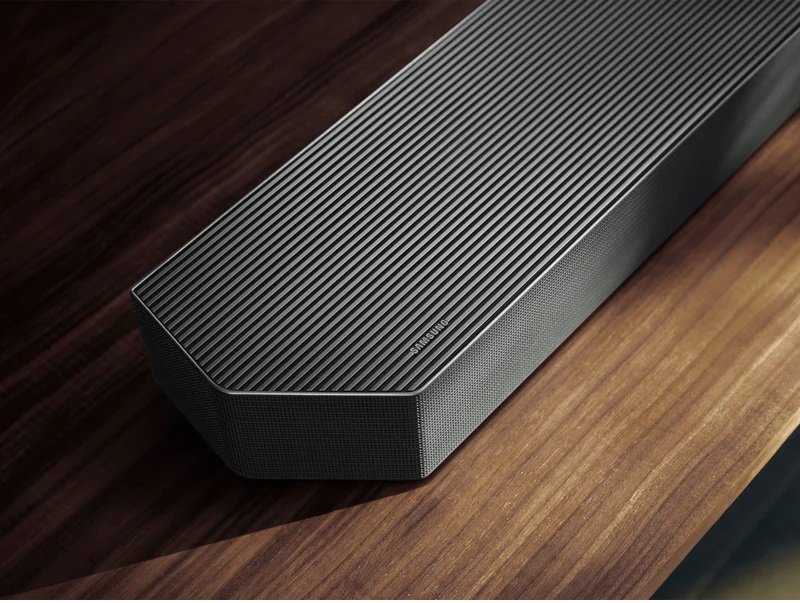 Gros plan de la barre de son élégante et moderne SAMSUNG HW-Q995D (Copie) sur une surface en bois, mettant en valeur son design haut de gamme et ses performances audio supérieures.