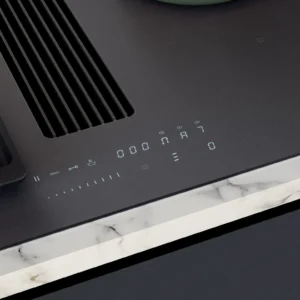 Gros plan de la table de cuisson NOVY 1861-G1 EASY MATT LINE avec commandes tactiles numériques, posée contre un bord de comptoir en marbre.