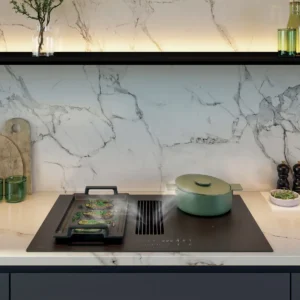 Cuisine moderne avec finition NOVY 1861-G1 EASY MATT LINE, dosseret en marbre, table de cuisson, pot vert, herbes sur une planche et vases décoratifs.