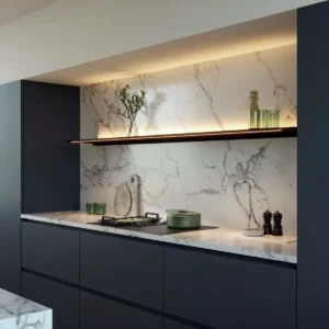 Cuisine moderne avec armoires foncées NOVY 1861-G1 EASY MATT LINE, dosseret en marbre, étagère ouverte et décor minimaliste sur le comptoir et l'étagère pour un look élégant et contemporain.
