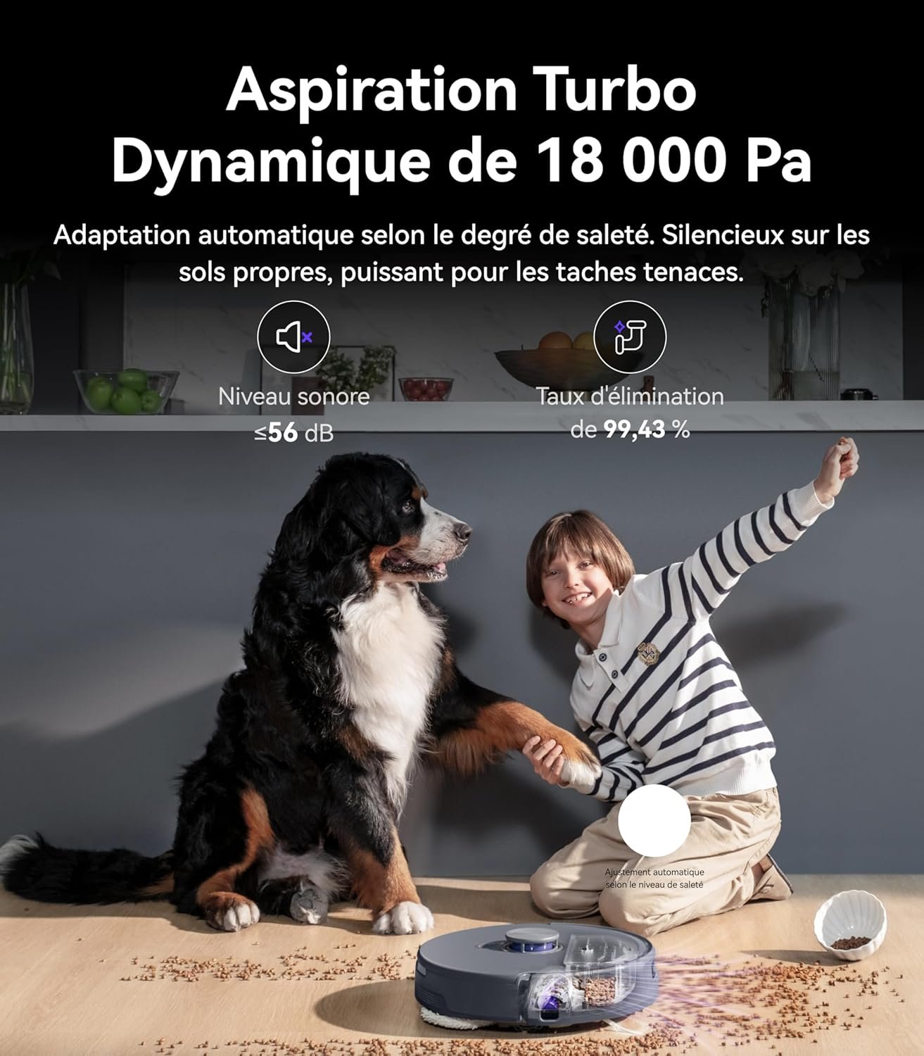 Un gros chien et un enfant souriant sont assis à côté de l'aspirateur robot NARWAL FREO Z10 ULTRA GRIS pendant qu'il nettoie les croquettes renversées sur le parquet.