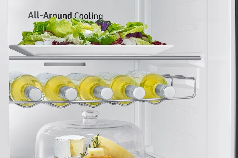 Une assiette de salade, des bouteilles de vin blanc et un plateau de fromages sont soigneusement disposés sur les étagères à l'intérieur du réfrigérateur SAMSUNG RS65DG54R3S9EF.