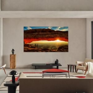 Un salon contemporain, orné d'un grand tableau de paysage, de baies vitrées et d'un mobilier minimaliste, incarne le style galerie. Un téléviseur LG OLED55G5 2025 GALLERY DESIGN s'intègre parfaitement au décor, rehaussant l'ambiance épurée.