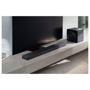 Un ensemble barre de son et caisson de basses noir SAMSUNG HW-QS760F repose sur un support TV de couleur claire sous un téléviseur à écran plat.