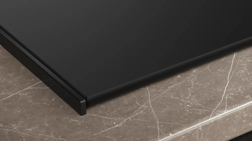 Gros plan d'un appareil rectangulaire noir SIEMENS STUDIOLINE EX87BNX68E sur une surface en marbre marron avec des veines de couleur claire.