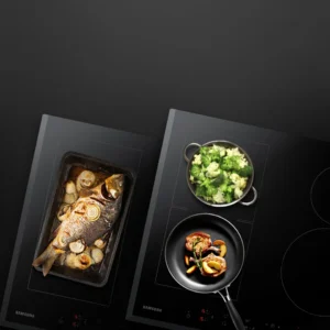 Vue de dessus du poisson avec des légumes, du brocoli dans une casserole et des légumes mélangés dans une poêle sur la plaque à induction noire SAMSUNG NZ63B6056GK.