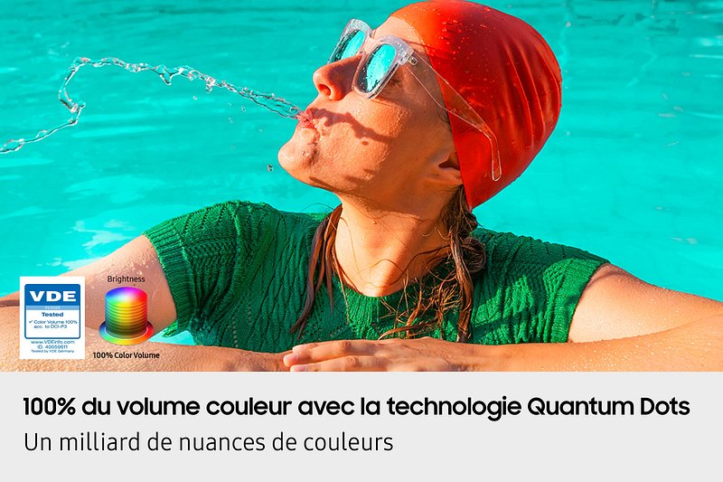 Une femme portant un bonnet de bain orange et des lunettes de soleil éclabousse l'eau, avec des couleurs vives et éclatantes sur l'écran SAMSUNG TQ55Q7F4AUXXC - ID de la scène : TQ55Q7F4AUXXC.