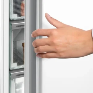 Une main ouvre la porte du réfrigérateur LIEBHERR FND7026-22, révélant ses spacieuses étagères blanches à l'intérieur.