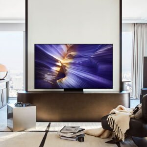 Salon moderne avec un téléviseur SAMSUNG TQ55S90F, un fauteuil noir et une vue imprenable sur la ville grâce à de grandes fenêtres.