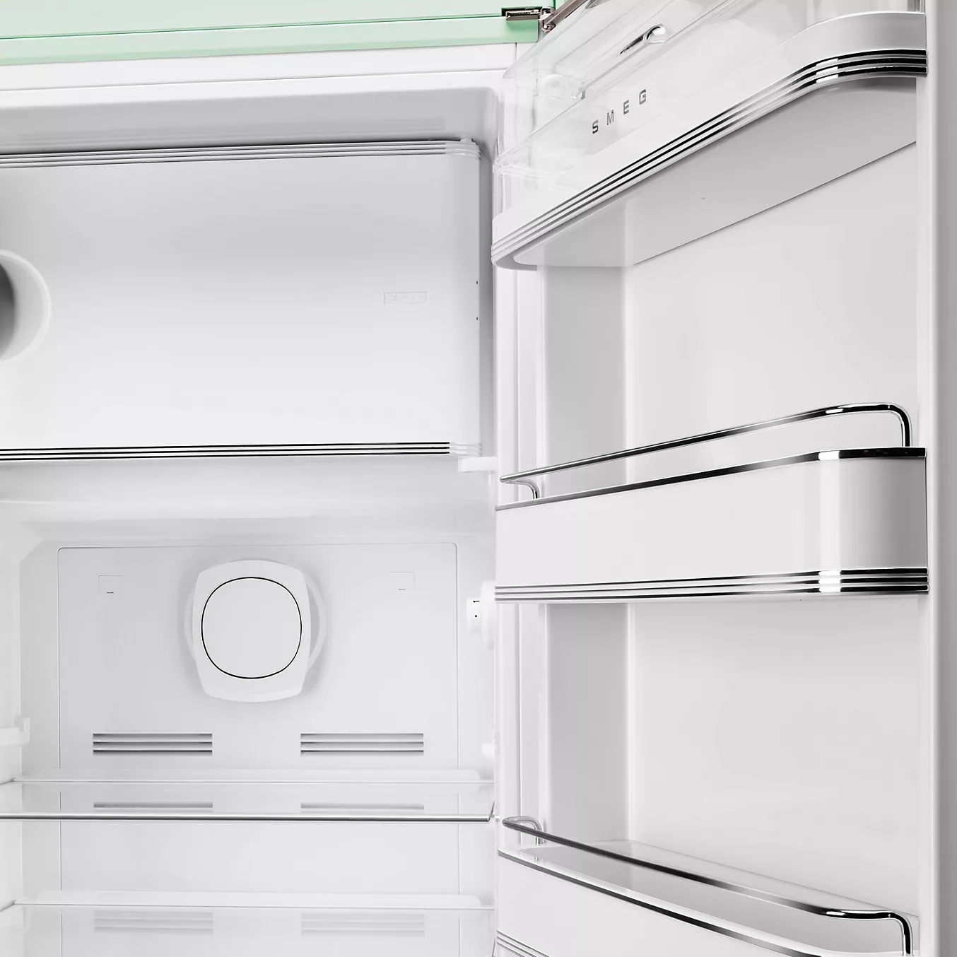 Le réfrigérateur rétro SMEG FAB28RPG6 présente un intérieur ouvert et vide avec des étagères en verre et des accents chromés sur la porte et à l'intérieur.