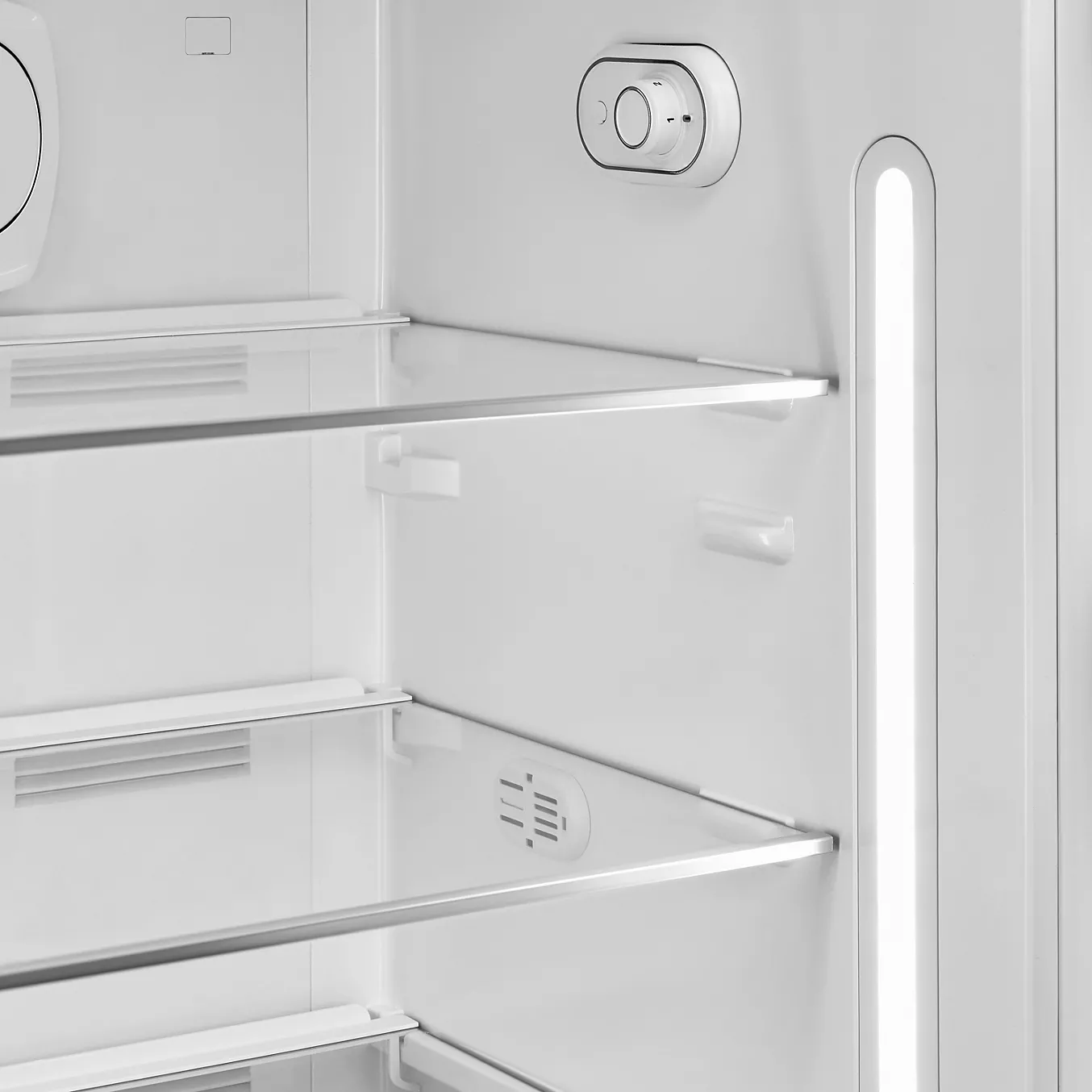 Gros plan des clayettes du réfrigérateur SMEG FAB28RPG6, mettant en évidence le bouton de réglage de la température et l'éclairage intérieur LED du côté droit.