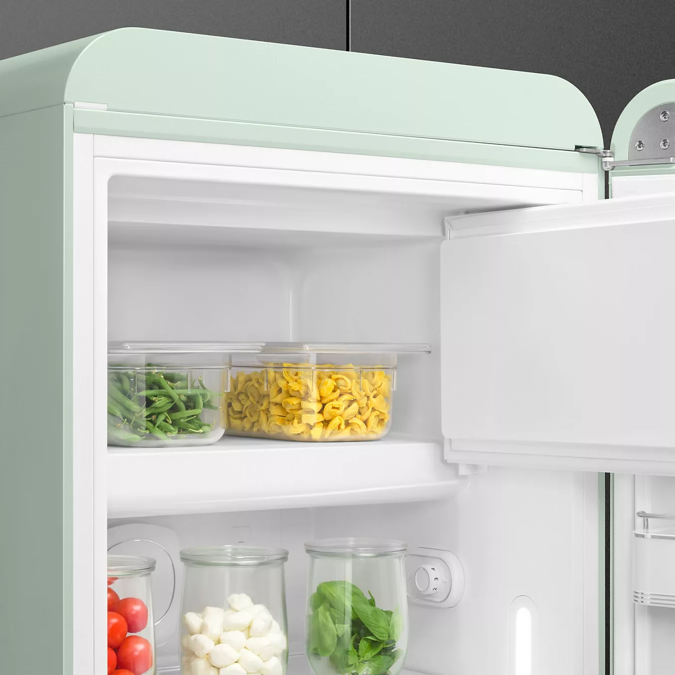 Ouvrez le SMEG FAB28RPG6 pour découvrir des récipients transparents remplis de haricots verts, de pâtes jaunes, de tomates, de fromage et d'épinards.