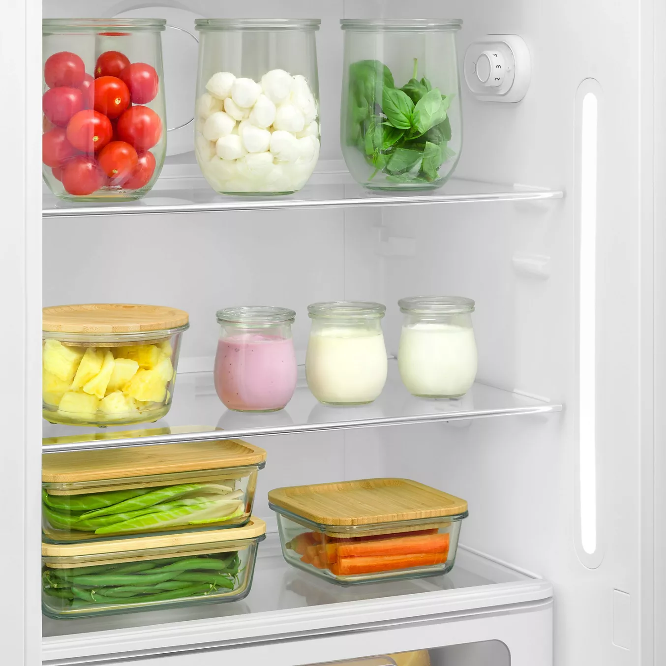 Les fruits, les légumes, les légumes verts et les yaourts sont soigneusement rangés dans des bocaux en verre à l'intérieur du réfrigérateur rétro SMEG FAB28RPG6.