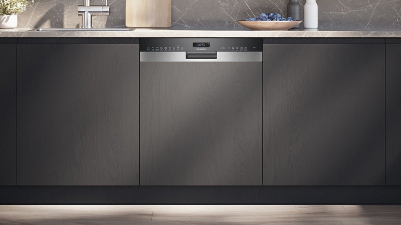 Le lave-vaisselle SIEMENS SN63H800MF - STUDIOLINE est parfaitement intégré dans les armoires de cuisine modernes et foncées, sous un comptoir en marbre, ajoutant la sophistication propre à Studioline.