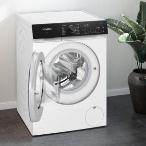 Le SIEMENS WG56H2A5FR, un lave-linge blanc à chargement frontal, est présenté avec sa porte ouverte dans une buanderie moderne.