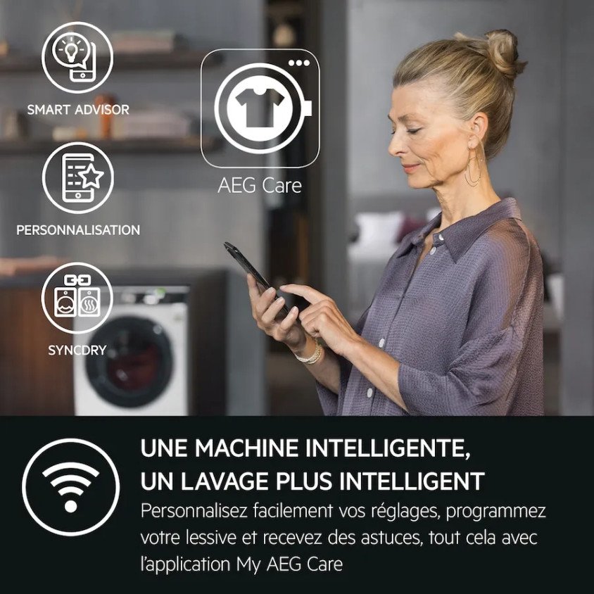 Une femme utilise son smartphone devant un lave-linge AEG LFR73A943V, mettant en avant ses fonctions de blanchisserie intelligente.