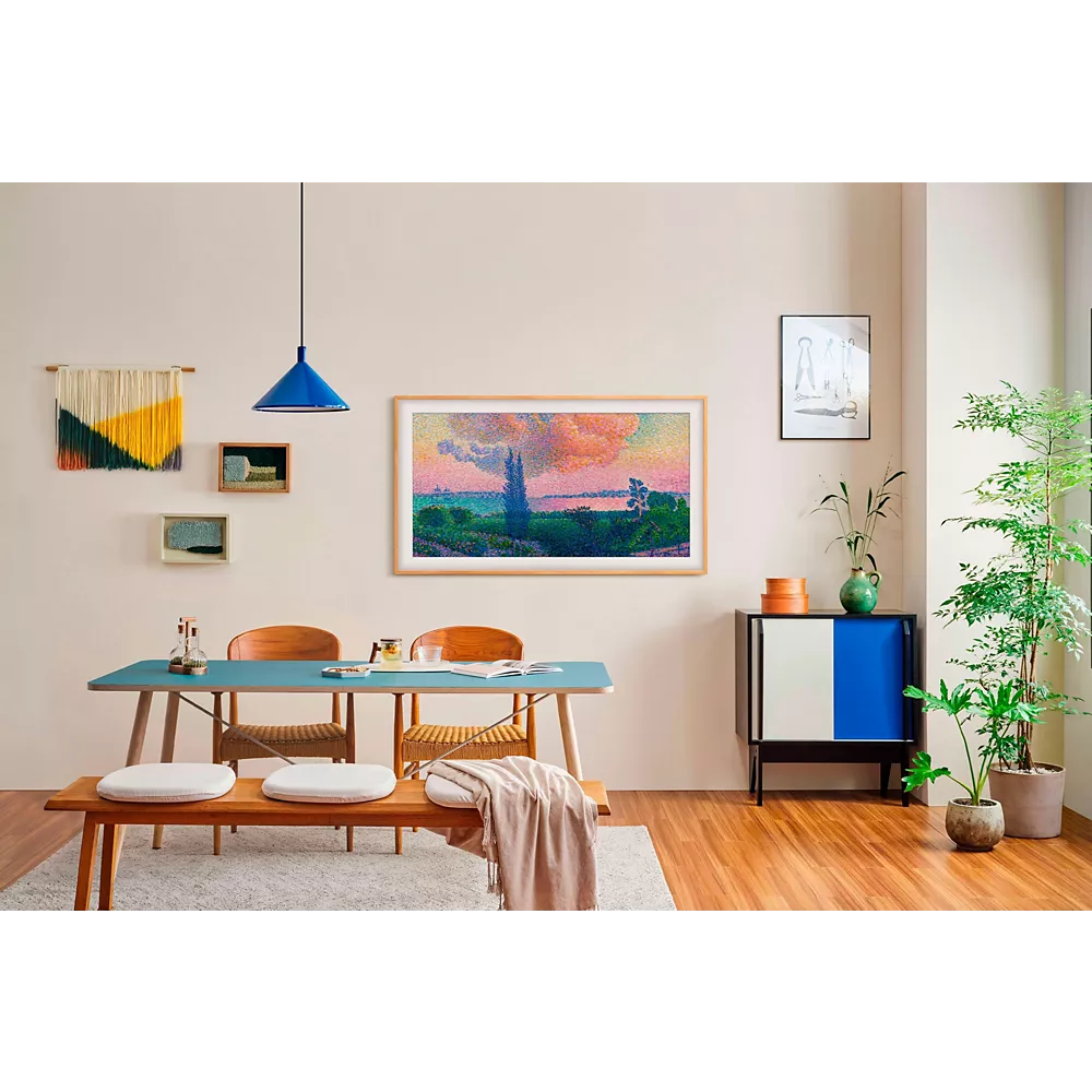 Salle à manger moderne avec meubles en bois, art mural vibrant sur le SAMSUNG TQ55LS03F THE FRAME, et plantes vertes sur un sol en bois dur.
