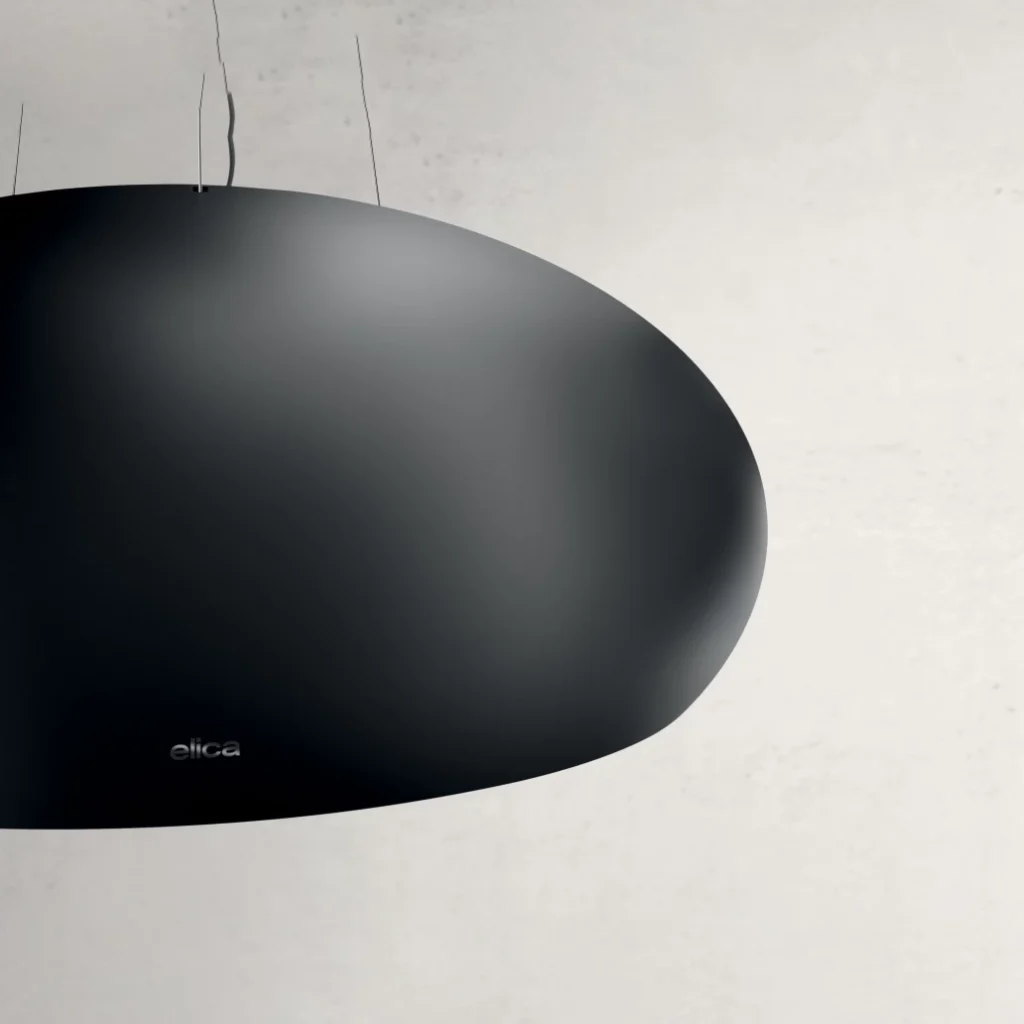 Gros plan sur la hotte de cuisine ELICA CRUISE IX/A/90 (Copie) avec une finition moderne en noir mat et un design ovale, montée avec style contre un mur uni.