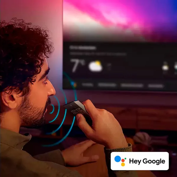 Un homme utilise une télécommande et une commande vocale pour interagir avec Google Assistant sur le téléviseur PHILIPS 55OLED850/12.