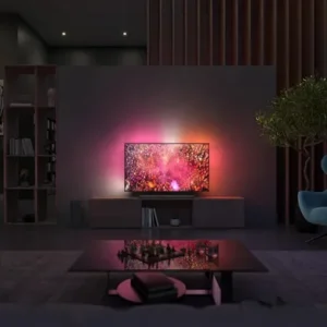 Un salon moderne présente le PHILIPS 65OLED850/12, un téléviseur OLED aux couleurs vives et à l'éclairage ambiant, fixé au mur.