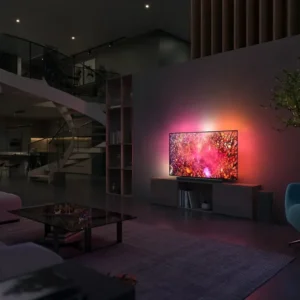 Salon moderne avec un téléviseur PHILIPS 65OLED850/12 OLED fixé au mur, des meubles élégants et un escalier en colimaçon en arrière-plan.