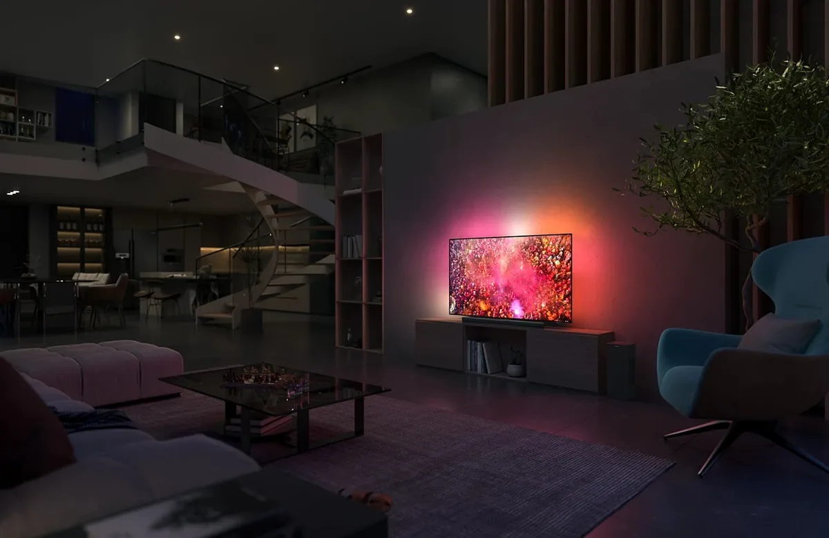 Salon moderne avec un téléviseur PHILIPS 65OLED850/12 OLED fixé au mur, des meubles élégants et un escalier en colimaçon en arrière-plan.