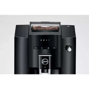 La machine à café JURA E4 PIANOBLACK présente une finition élégante en noir piano avec des grains de café visibles dans le compartiment supérieur, vu de face.