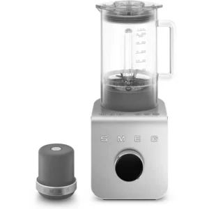 Mixeur SMEG BLC01BLMEU comprenant un pichet transparent, une base argentée et un accessoire gris coordonné placé à côté.