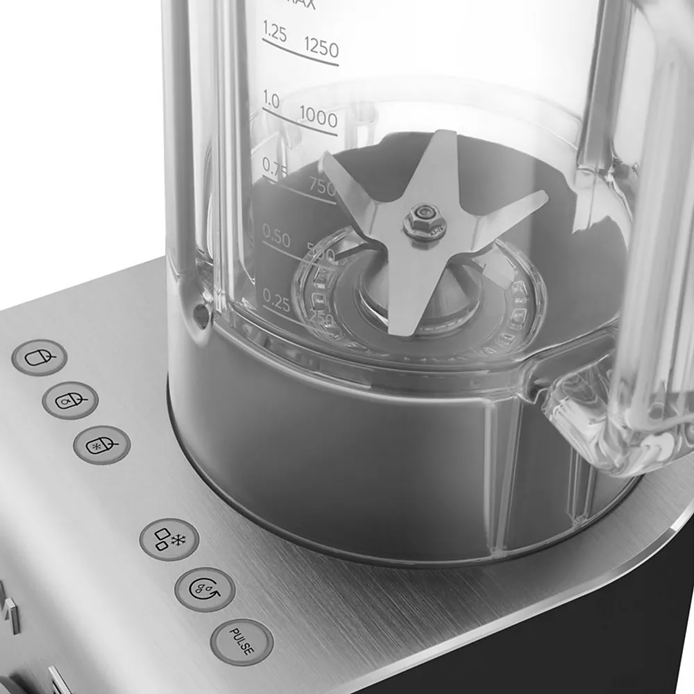 Gros plan sur le blender SMEG BLC01BLMEU, mettant en évidence ses lames métalliques tranchantes et ses boutons de commande sur une élégante base en acier inoxydable.