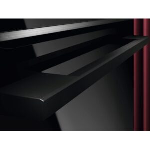 Une élégante étagère flottante noire est montée sur un mur noir brillant avec un rideau rouge à proximité, mettant en valeur l'aspect contemporain et le style moderne de l'appareil AEG TR7PB731SB.