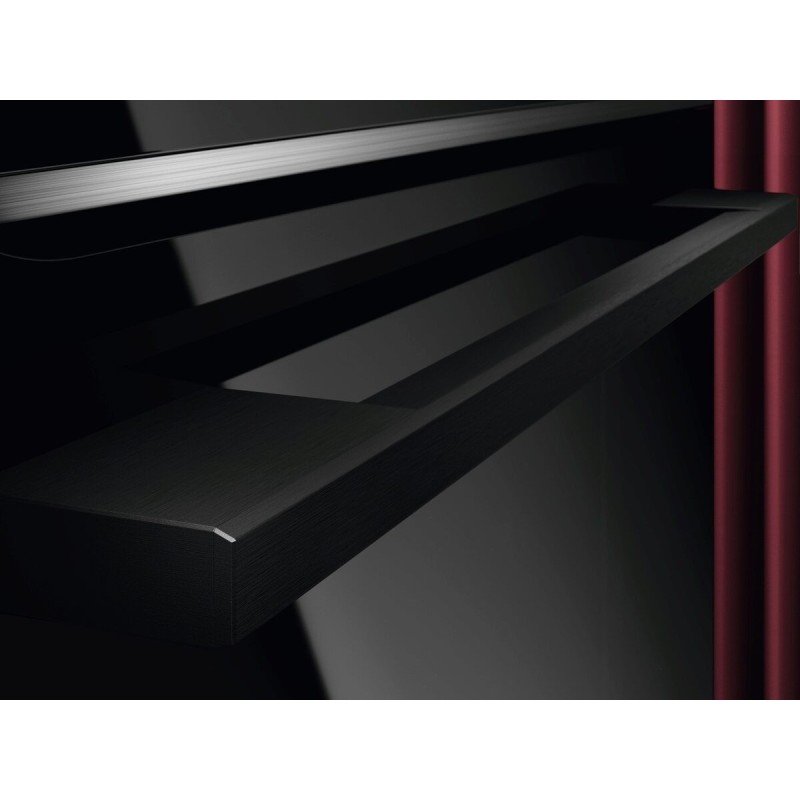 Une élégante étagère flottante noire est montée sur un mur noir brillant avec un rideau rouge à proximité, mettant en valeur l'aspect contemporain et le style moderne de l'appareil AEG TR7PB731SB.